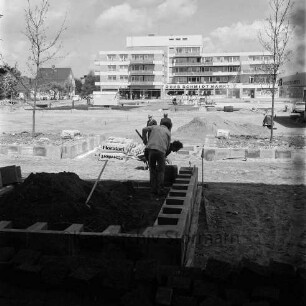 Rathausplatz: in Bau: Anlegen der Baum- und Blumenbeete: Blick Richtung Norden auf die moderne Randbebauung: hinten links Reeshoop (später Manfred-Samusch-Straße)