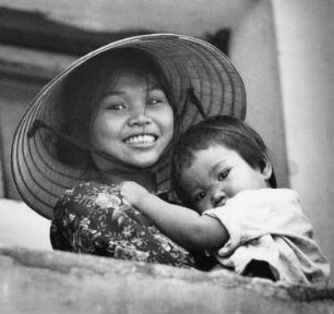 Vinh. Frau mit Reisstrohhut mit ihrem Kind