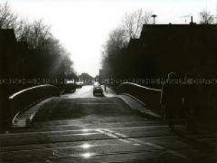 Blick auf eine Brücke im Gegenlicht, im Vordergrund rechts altes Ehepaar (Altersgruppe 14-17)