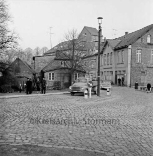 Matthias-Claudius-Straße / vorne rechts Kreuzung mit Klosterstraße: Kopfsteinpflaster: Verkehrsinsel mit Straßenlampe, Verkehrsschild, Wegweiser: Lkw, Fußgänger: Bildmitte links Kocksche Schmiede, Baum: im Hintergrund Claudius-Mühle