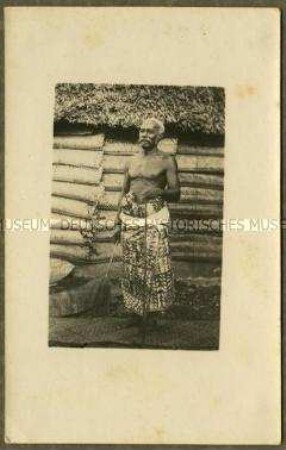 Alter afrikanischer Mann vor einer Hütte
