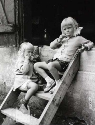 Dänemark. Nordby. Wie kleine Seehunde sehen die glatten Gesichter der dänischen Fischerkinder aus. (zwei blonde Mädchen beim Eisessen auf einer Holztreppe sitzend)