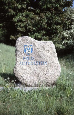 Langniendorf: Grenzstein zum Kreis Ostholstein: darauf Kreiswappen Ostholstein: neben der B 206
