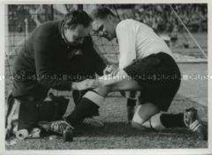 Physiotherapeut Erich Deuser behandelt verletzten Fußballspieler auf dem Spielfeld