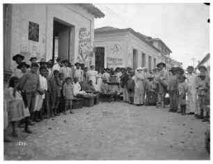 Puerto Cabello (Venezuela). Einheimische, Kinder, Backwarenhändler mit ihren Waren und Touristen, rechts ein Mann mit einem Lastesel
