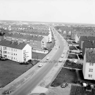 Gartenstadt Falkenberg: Blick vom Rathaus Richtung Osten: Stonsdorfer Weg mit parkenden Pkws auf Seitenstreifen: rechts und links Wohnblocks: dazwischen Grünflächen: im Hintergrund das Gewerbegebiet Stonsdorf