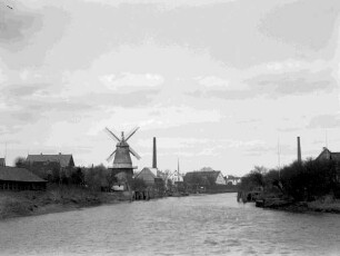 Ortschaft mit Windmühle an einem Wasserlauf