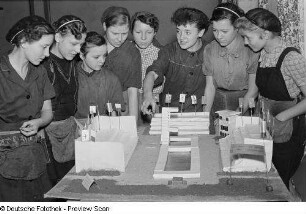 Eine Gruppe von Mädchen um ein Modell einer Sportanlage
