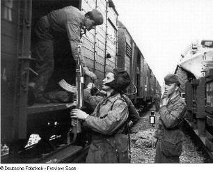 Deutschland . Truppenübungsplatz Klietz. Nationale Volksarmee - Landstreitkräfte. Truppenverlegung per Eisenbahnmarsch. Soldaten zwischen zwei Militärzügen (rechts Flachwagen mit Militärtechnik, links Mannschaftswagen)