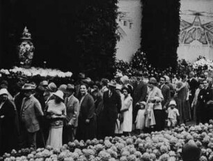 Szene aus dem Dokumentarfilm "Bilder von der Frühjahrsblumen-Eröffnungsschau der Jubiläums-Gartenbau-Ausstellung": Besucher auf dem Ausstellungsgelände