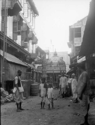 Bombay. Straße mit zwei posierenden Jungen gegen ein kleines Hindu-Heiligtum