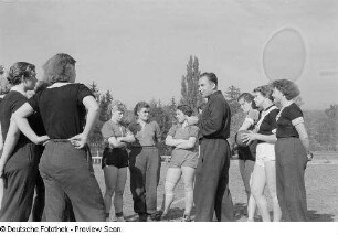 Portrait eines Trainers und mehreren Sportlerinnen auf dem Sportplatz der Sportschule