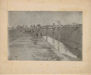 Soldaten auf provisorischer Brücke über Wassergraben.