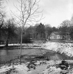 Lasbek-Gut: Lasbeker Mühlenteich: Blick nach Abriss der Lasbeker Mühle: im Hintergrund Gebäude zwischen Bäumen: Winter