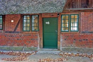 Nütschau: Schloßstraße 42a-c: traufständige Mehrfamilienkate aus Fachwerk mit Reetdach: Straßenfront, Teilansicht: Eingangstür, Sprossenfenster, Heuluke