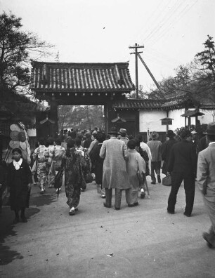 Kyōto. Besucher auf dem Blütenfest (wahrscheinlich im Februar zur Pflaumenblüte auf dem Gelände des Kitano Tenmangū Schreins im Norden der Stadt). Besucher vor dem Eingangstor