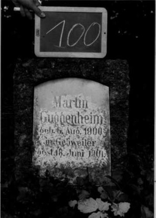 Grabstein 100 (Index: 100110371) Material: Granit mit weißer Marmorplatte Zustand: verwittert Maße HxBxT: 60x43x29 cm Beschreibung: Stele, flacher Abschluß, Schriftplatte mit Segmentbogen Besonderheit: Kindergrab: Grabstein 100