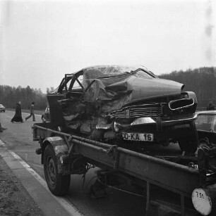 B 404: bei Nütschau: Verkehrsunfall: Zusammenstoß von zwei Pkws: Unfall-Pkw mit eingedrückter Karosserie auf Hänger von Abschleppwagen: an Straßenrand Glassplitter: hinten Bruder von Kloster Nütschau und Mann bei Überqueren der Straße, 2. März 1974