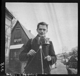 Fotograf mit Balgenkamera und Stativ auf einer Straße in einem Ort