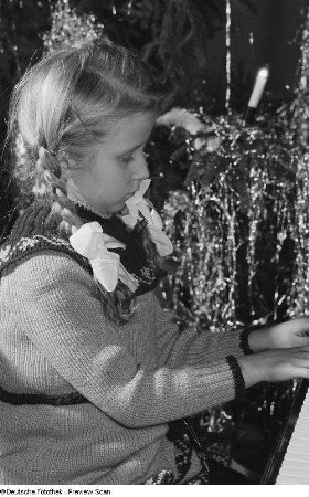 Ein Mädchen am Klavier auf der Weihnachtsfeier für Kinder der Betriebsangehörigen der HO Lebensmittel Leipzig West