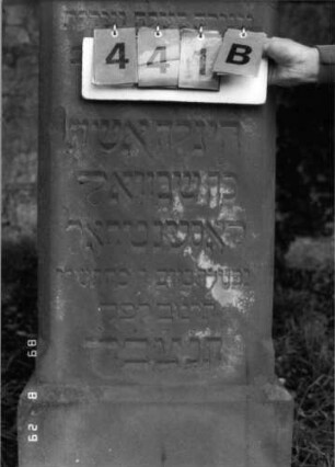 Grabstein 441 (Index: 100107971) Material: roter Sandstein Zustand: versalzen Maße HxBxT: 149x46x27 cm Beschreibung: Stele mit Giebelaufsatz, Seitenkanten stark abgephast, Sockel: Grabstein 441B