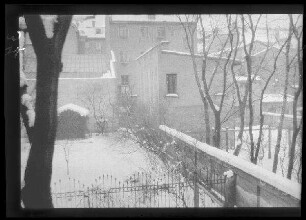 Blick auf einen verschneiten Garten innerhalb einer Ortschaft