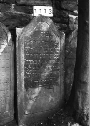 Grabstein 1113 (Index: 99630616) Material: Sandstein Zustand: verwittert Maße HxBxT: 121x61x12 cm Beschreibung: Stele mit Konvexbogenabschluß, Schriftfeld eingetieft: Grabstein 1113 (Nachholaufnahme)