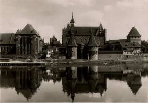 Ansicht der im 13. Jahrhundert erbauten mittelalterlichen Marienburg/Westpreußen (heute Zamek w Malborku) von Westen über den Nogat. In der Bildmitte das Brückentor