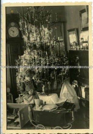 Mädchen mit Puppenspielzeug unter dem Weihnachtsbaum