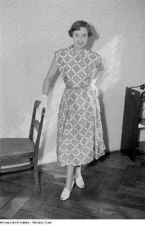 Eine Frau posiert mit Sommerkleid an einem Stuhl bei der "Internationalen Messemodenschau", Herbstmesse 1953