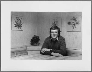 Winfried Kretschmann an einem Tisch sitzend zuhause