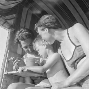 Elisabeth Gremmler sitzt rechts in einem Strandkorb mit ihrem Kind und einer rauchenden Frau