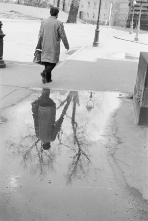 Spiegelungen. Straßenpassant, in einer Pfütze gespiegelt
