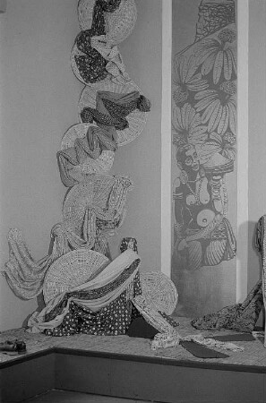 Eine Auslage mit verschiedenen drapierten Stoffen und einem exotischen Wandbild auf der Leipziger Herbstmesse 1955