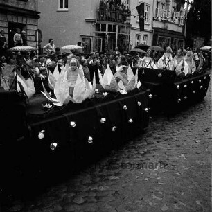 Karpfenfest: Umzug: Festwagen, kleine Mädchen als Seerosen: dahinter am Straßenrand und auf Balkon Zuschauer, mit Regenschirmen, Hausfassaden mit Fahnenschmuck, Wimpelgirlanden, 8. Oktober 1961