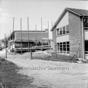 Realschule Harksheide: Fadens Tannen: Erweiterungsbau: Rohbau mit Gerüst: vorn Altbau: davor Zaun und Einfahrt: links Baumaterial