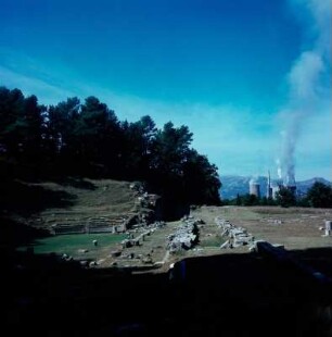 Theater (Ruine), Megalopolis : Megalopolis. Blick in das antike Theater von der Seite und auf die Sockelmauern des Thersileions. Im Hintergrund modernes Kraftwerk, 1976