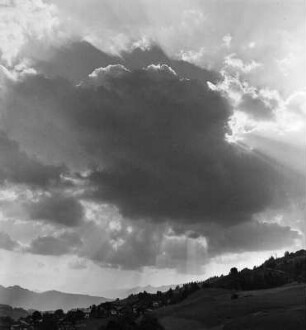 Wolkenbilder. Wolken mit untergehender Sonne über Gebirgslandschaft
