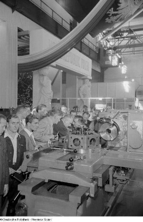 Besucher der Technischen Messe 1953 betrachten in der polnischen Ausstellungshalle eine Werkzeugmaschine