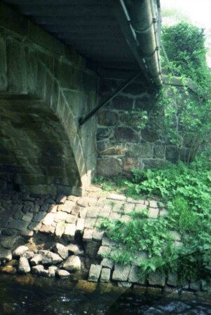 Bestestraße: Granitquader-Brücke über die Beste: Blick von unten: Brückenbogen, Unterseite Fahrbahn: Uferbefestigung mit Schäden