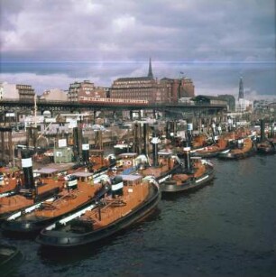 Hamburg. Hafen. Landungsbrücken. Eine Flotte von Barkassen liegt im Hafen, im Hintergrund die U-Bahn zwischen Baumwall und Landungsbrücken