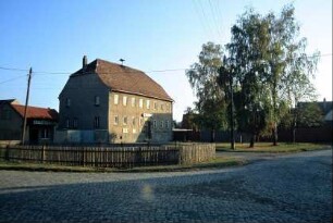 Dorfplatz mit umzäuntem Dorfteich; im Hintergrund Gaststätte; Birkengruppe auf Grünfläche