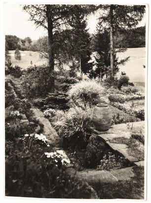 Garten Leo van den Bergh, Berlin-Kladow: Blumenbeet mit Plattenweg und Mauern, Golfplatz im Hintergrund