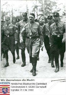 Hitler, Adolf (1889-1945) / Porträt in NS-Uniform mit Parteigenossen auf dem Weg nach Harzburg, mit Bildlegende 'Wir übernehmen die Macht'