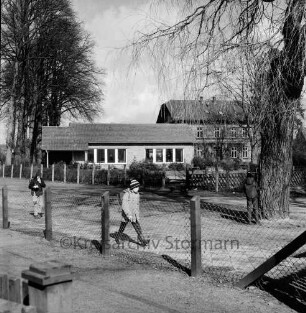 Evangelischer Kindergarten: Lindenstraße: rechts hinten Pastorat: im Vordergrund Kinder auf Kirchweg, Maschendrahtzaun: hinten links Bäume des Kirchhofs