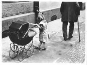 Kleines Mädchen mit Puppenwagen