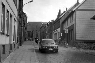 Gadebusch (Mecklenburg-Vorpommern) [Partnerstadt von Trittau]: Steinstraße: Auto, Motorräder: rechts Einmündung von Schulstraße, Personen vor Eiscafé Roller: hinten Stadtkirche St. Jakob und St. Dionysius
