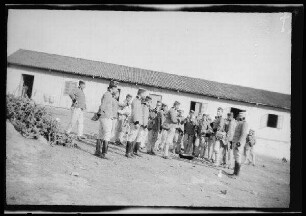 Nador (Marokko): Offiziere [des spanischen 8. Kavallerie-Regiments "Lusitania"] in hellgestreiften Uniformhosen, dunklen Uniformjacken mit Totenkopf-Abzeichen am Kragen und niedrigen, runden Feldmützen rund um ein am Boden stehendes flaches Gefäß vor dem "Rancho der 1. Eskadron"