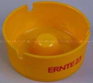 Aschenbecher (gelb) mit Werbeaufdruck für "Ernte 23"-Zigaretten