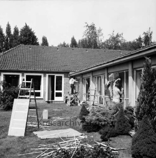 Emil-Nolde-Schule [Grundschule, früher Volksschule am Schweinemarkt]: Am Schulzentrum: Zwischenbau: Außenansicht: Einbau von Isolierglasscheiben: Handwerker, Leitern, Glasscheibe, Metallschienen